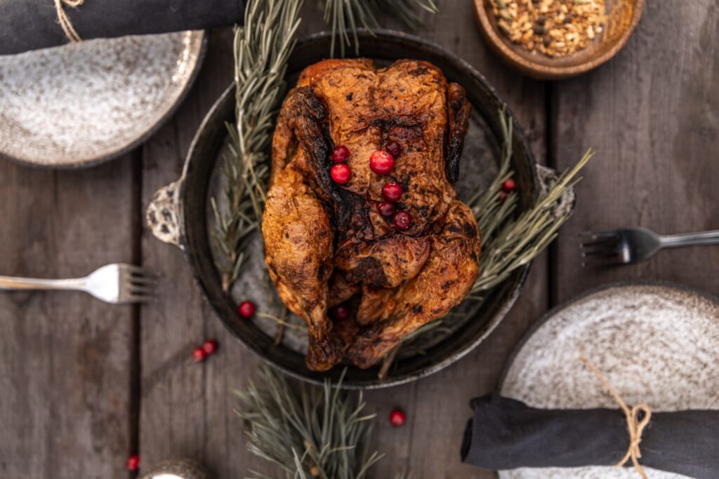 Cooked turkey with fresh sage sitting in a pan resting on a table.