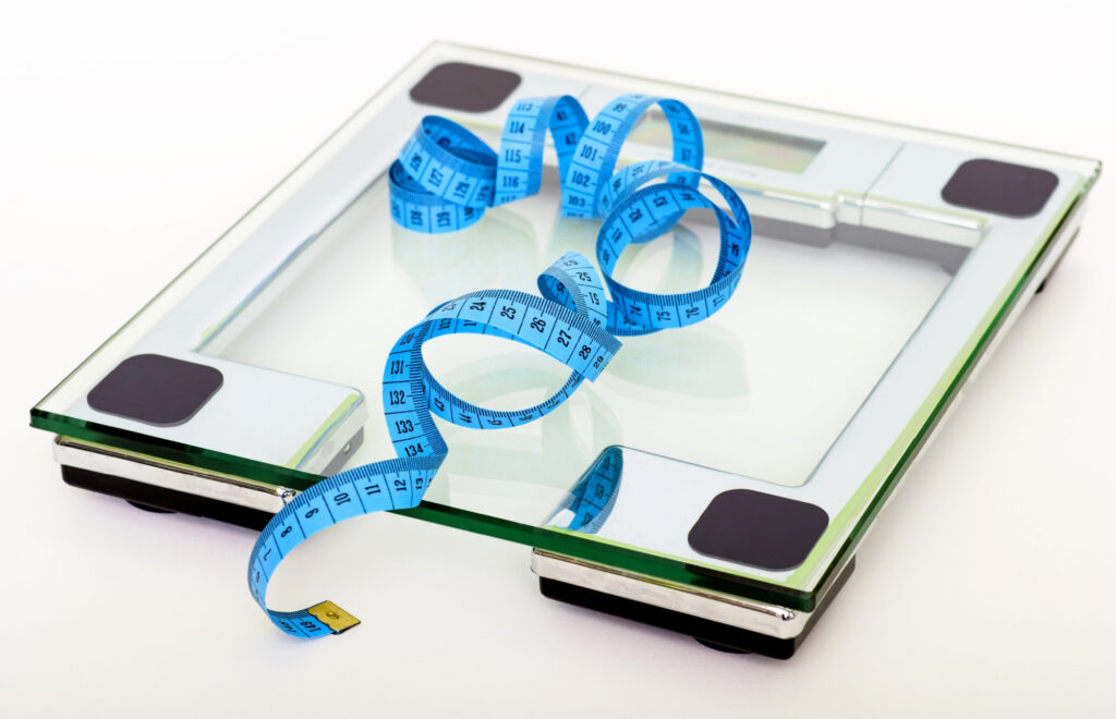 A transparent scale with a blue tape measure on top.