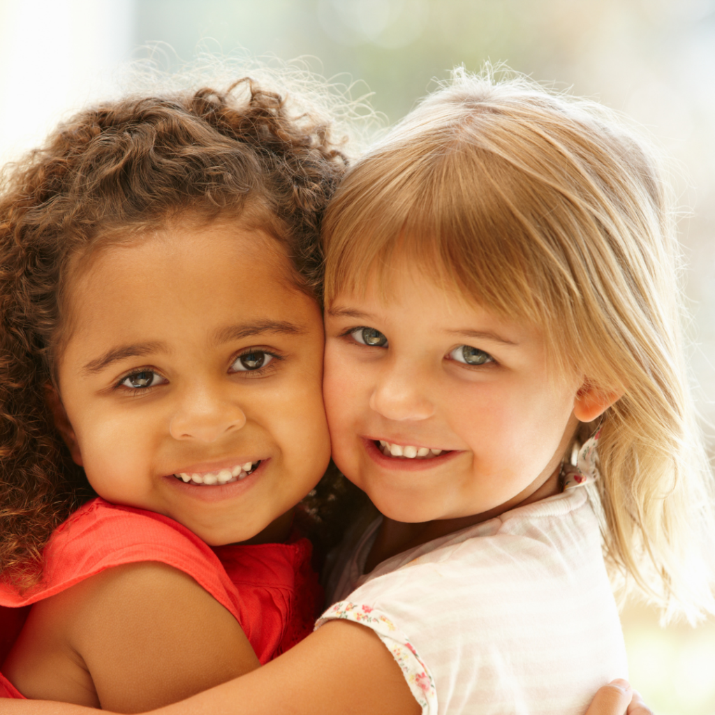 Two little girls hugging and smiling.