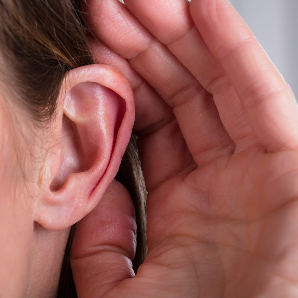 Close-up of a woman's ear with her hand behind it, and hair.