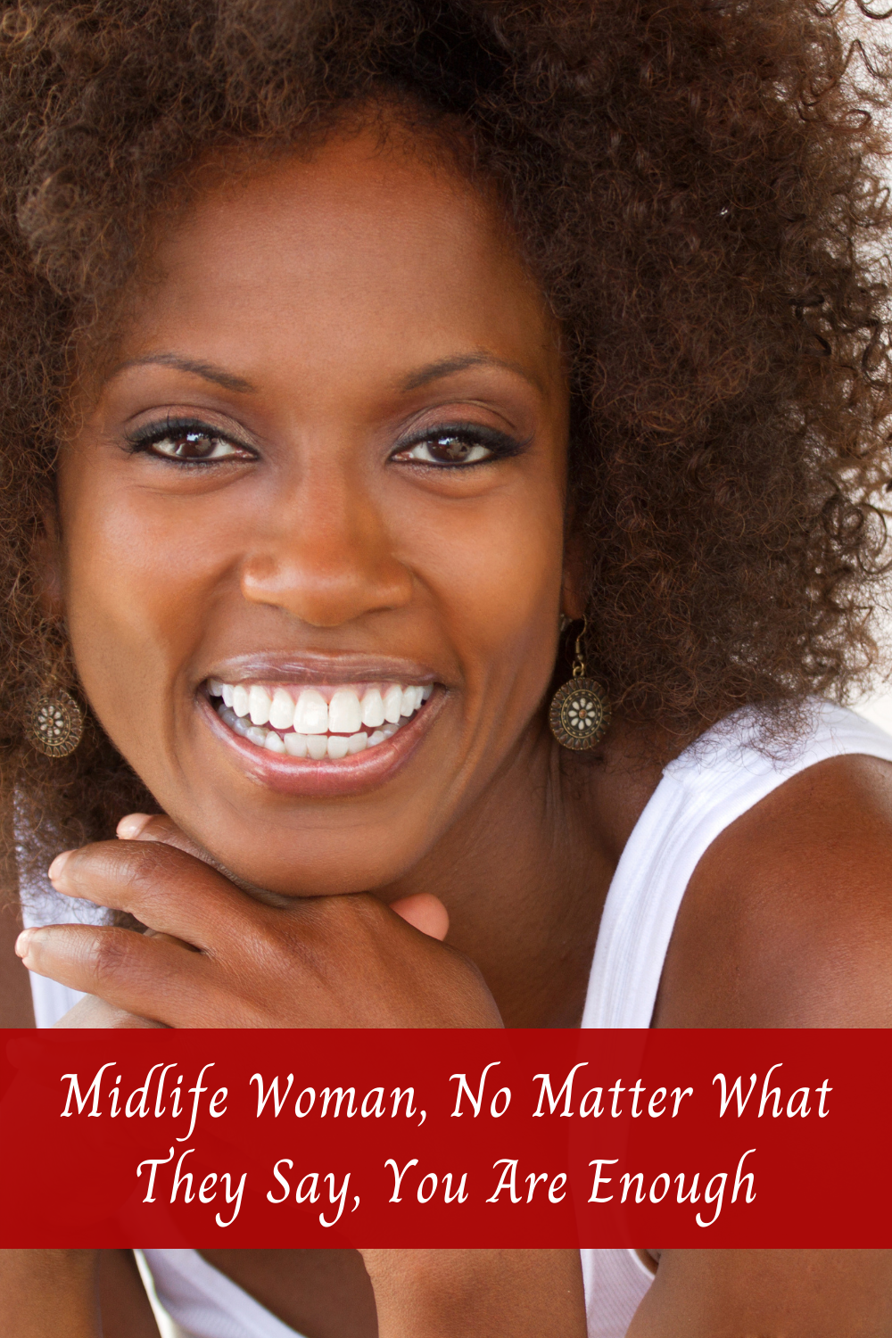 A smiling African-American woman wearing a white top with her hands crossed under her chin.